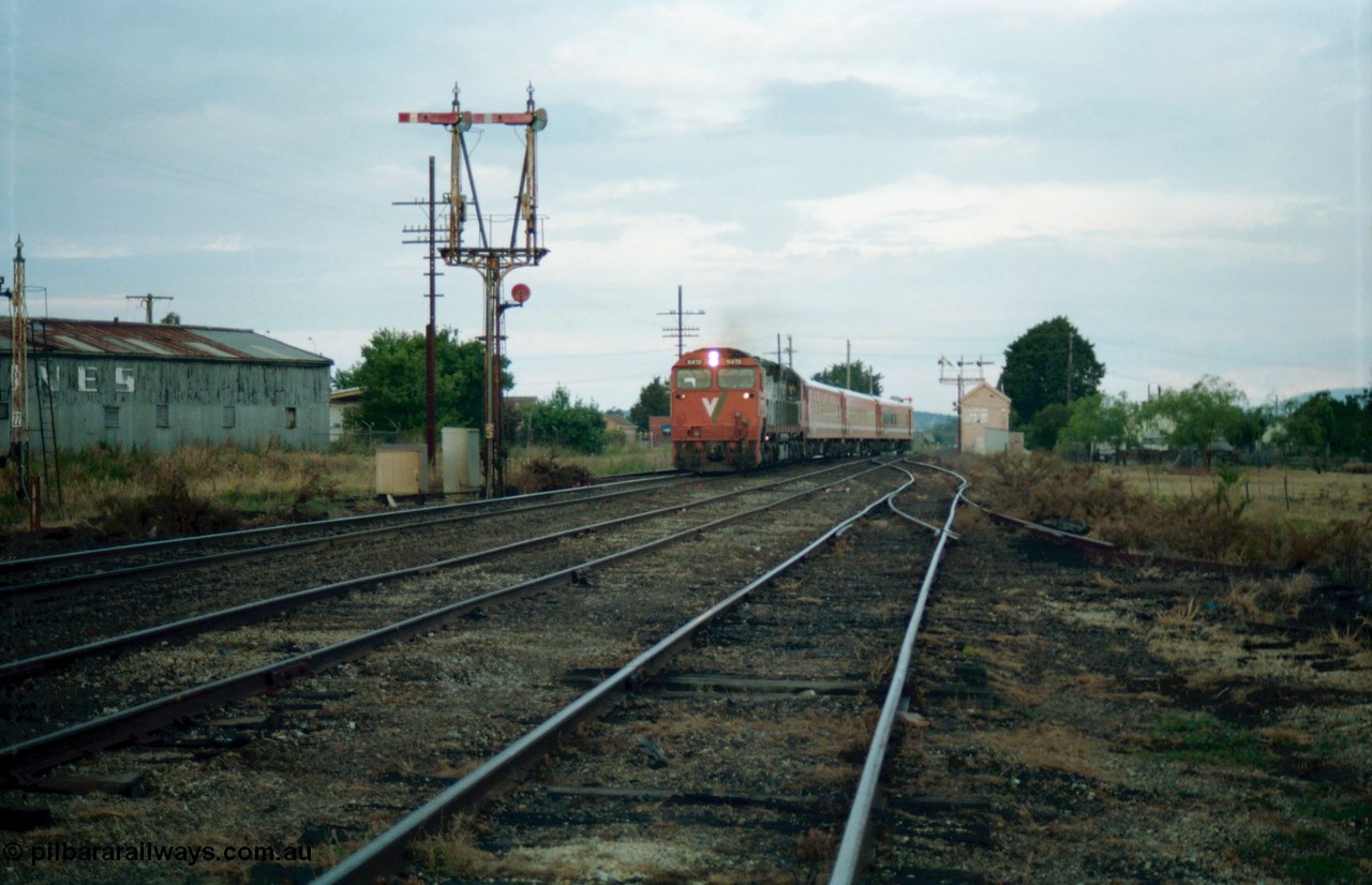159-15
Ballarat D Signal Box, Linton Junction, broad gauge V/Line N class N 472 'City of Sale' Clyde Engineering EMD model JT22HC-2 serial 87-1201 leads a down Dimboola passenger train with an N set, swings across onto the main western line having got the electric staff for the section to Trawalla, disc signal post 22 for Timken's Siding is just visible at the left, with up home semaphore signal post 23, line in the middle is the Linton Line, taken from the Cattle Yards Line. Semaphore signal post 20 can be seen pulled off for the move in the distance behind the signal box.
Keywords: N-class;N472;Clyde-Engineering-Somerton-Victoria;EMD;JT22HC-2;87-1201;