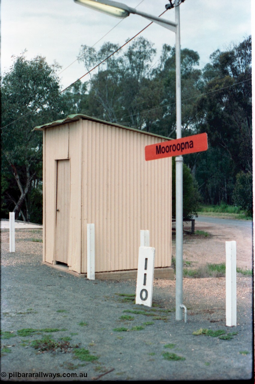 160-16
Mooroopna, 110 Mile Post and station name sign planted in the platform, the building behind it is a lamp room or WC?
