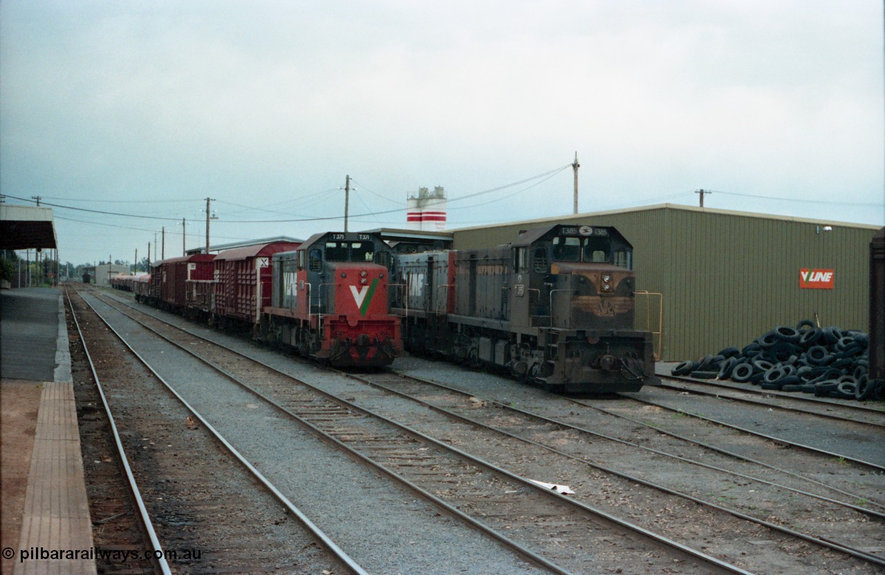 160-17
Shepparton, station yard overview looking south towards Melbourne from platform, stabled V/Line broad gauge T class locomotives T 371 Clyde Engineering EMD model G8B serial 64-326, T 385 serial 64-340 still in Victorian Railways blue and yellow and T 393 serial 65-423 behind T 385, T 371 is on a stabled down Shepparton goods train in No.3 Rd, while T 385 and T 393 worked the down Shepparton fuel train and is stabled on No.4 Rd, goods shed behind and pile of traction tyres at right.
Keywords: T-class;T371;Clyde-Engineering-Granville-NSW;EMD;G8B;64-326;