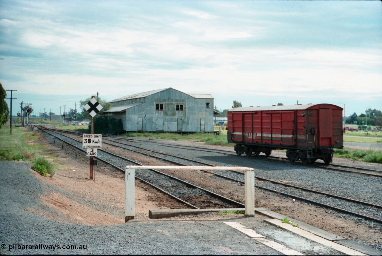 161-19
Cobram, station yard overview looking south from the platform, searchlight signal post and grade crossing with speed board and indicator, corrugated iron shed, V/Line broad gauge D type bogie louvre van in yard having being shunted off an earlier down passenger train.
