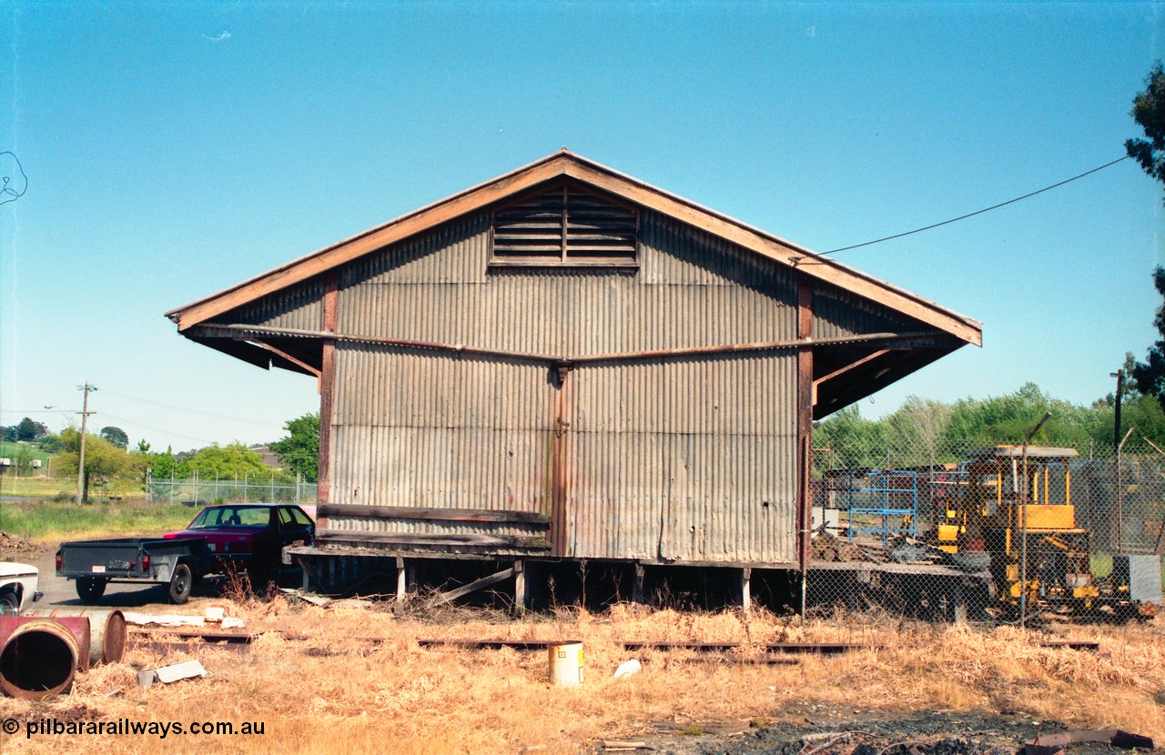 162-1-02
Healesville, view of goods shed, eastern side elevation and loading platform, fenced off compound with track machines, standard Victorian Railways 20 ft goods shed.
