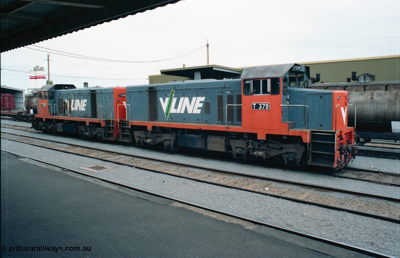 163-24
Shepparton station view from platform with stabled V/Line broad gauge T class locomotives T 379 Clyde Engineering EMD model G8B serial 64-334 and T 384 serial 64-339 next to the fuel train they operated the night before, goods shed is behind the consist, Freightgate and cement silos in the background.
Keywords: T-class;T379;Clyde-Engineering-Granville-NSW;EMD;G8B;64-334;
