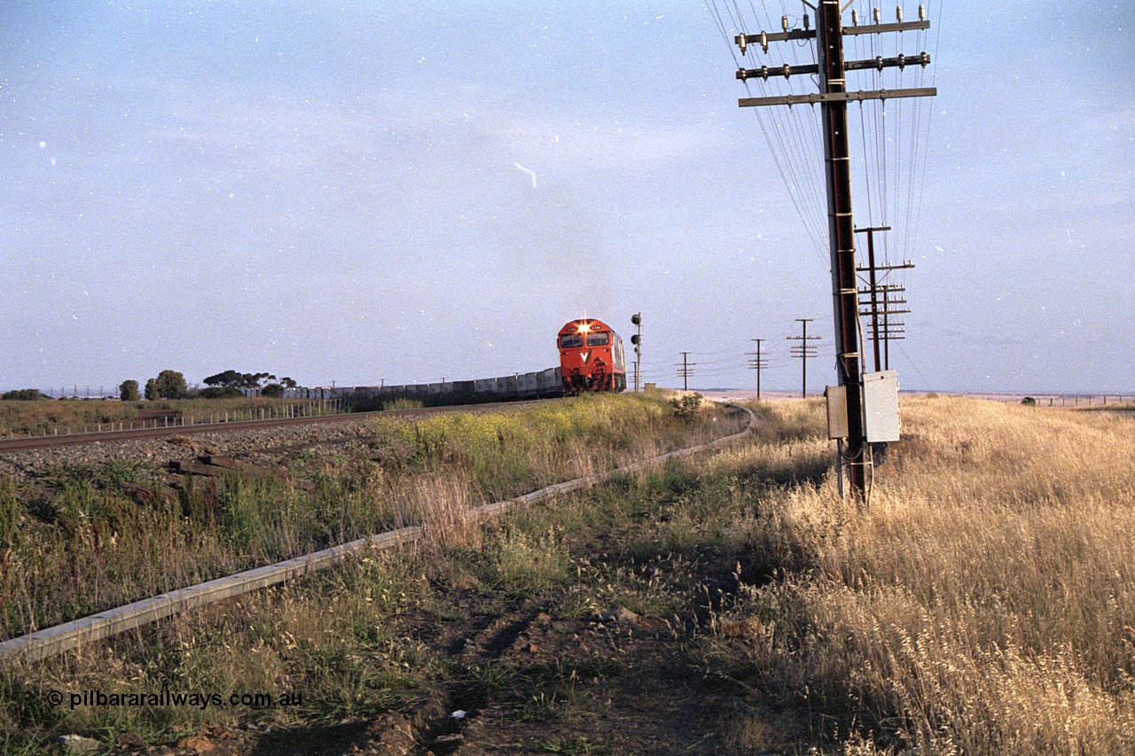 168-03
Bank Box Loop, down V/Line broad gauge goods train to Adelaide behind G class G 540 Clyde Engineering EMD model JT26C-2SS serial 89-1273 and Australian National 700 class 704 AE Goodwin ALCo model DL500G serial G6059-2 round the curve past the down home searchlight signal post.
Keywords: G-class;G540;Clyde-Engineering-Somerton-Victoria;EMD;JT26C-2SS;89-1273;