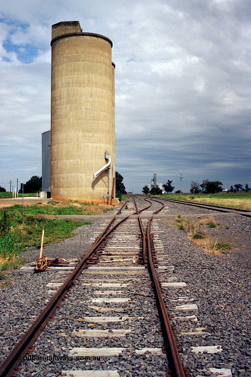 170-05
Dookie, yard overview looking west, crossover with hand locking bar to mainline on the right, gravitational road runs along the front of the Williamstown style silo complex with steel annex visible, GEB sub-terminal in the background.
