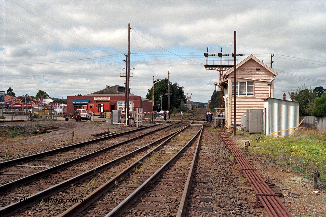171-04
Ballarat, Linton Junction signal box Gillies St, work site view, interlocked gates being replaced by boom barriers, view of signal box, triple doll semaphore signal Post 20, Timken's Siding disc signal Post 21, staff exchange platform and auto exchange apparatus cover open, track view, point rodding, exchange apparatus gauge leaning against toilet building, standing on Linton line.
