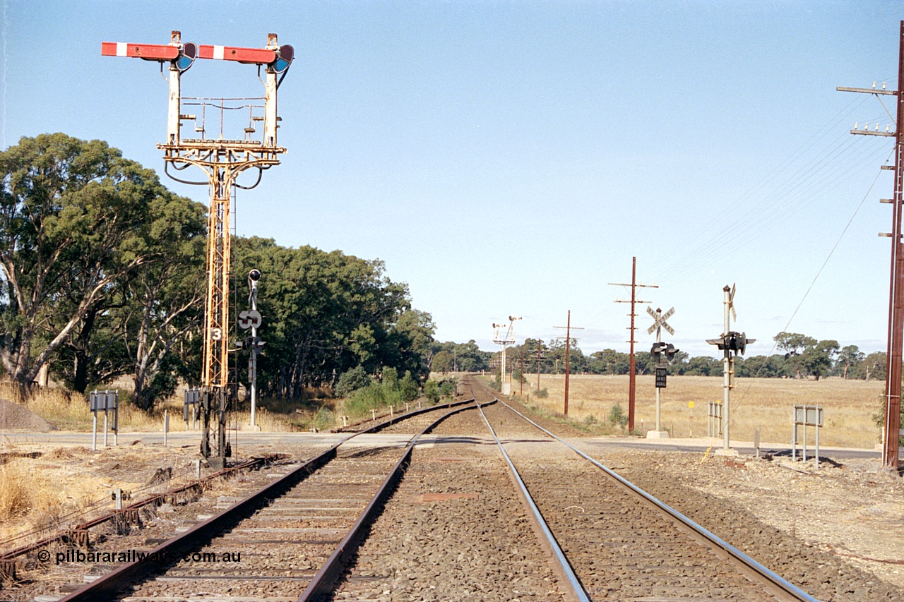 171-17
Buangor station yard overview, looking towards Melbourne, east end of loop, up home semaphore signal Post 3, point rodding and signal wires, High Street grade crossing and semaphore signal Post 2 facing down trains in the distance.
