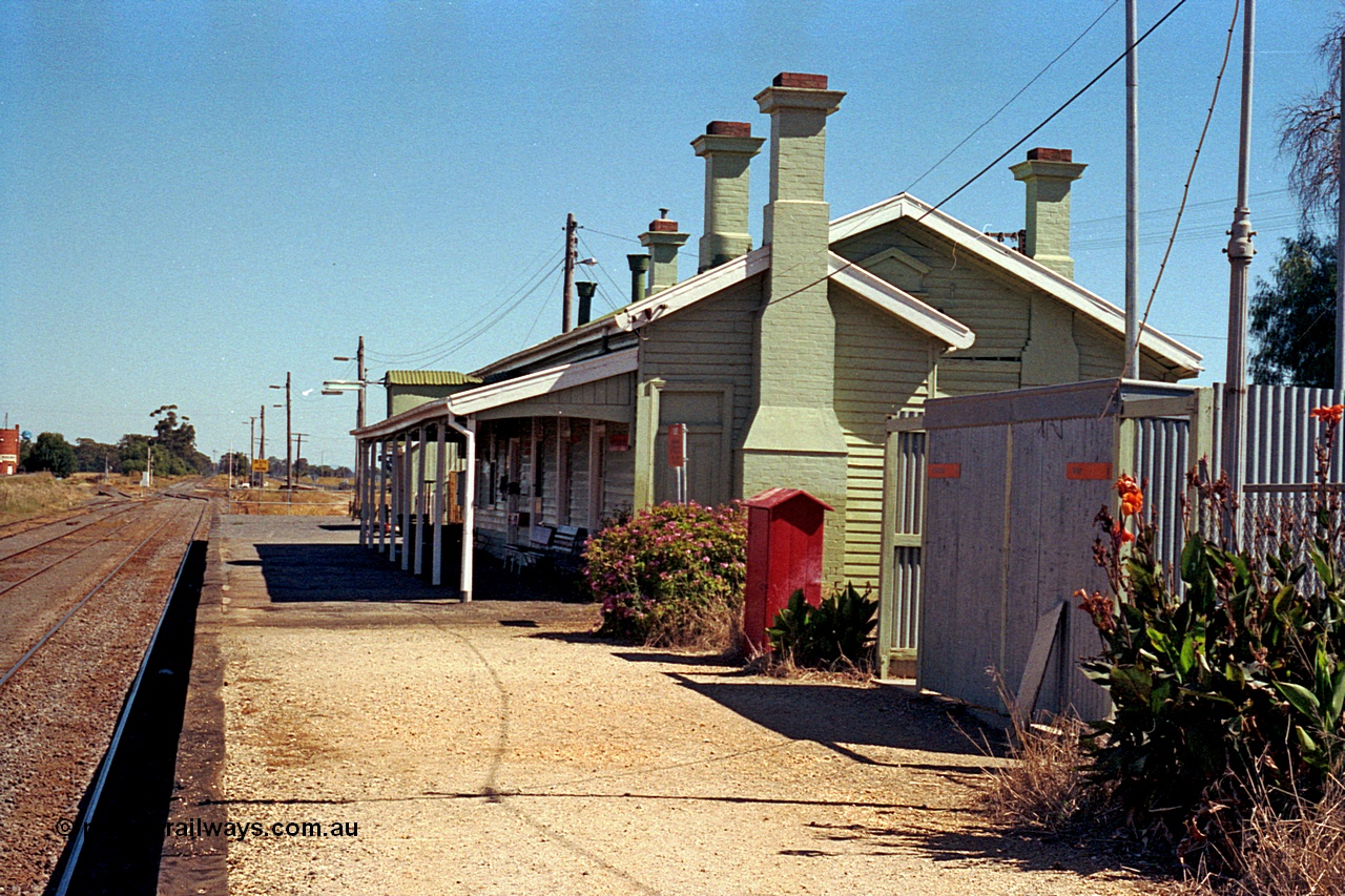 173-15
Murchison East, station building and platform overview looking south towards Melbourne, ablution block, fire hose cabinet, station building with a number of brick chimneys.

