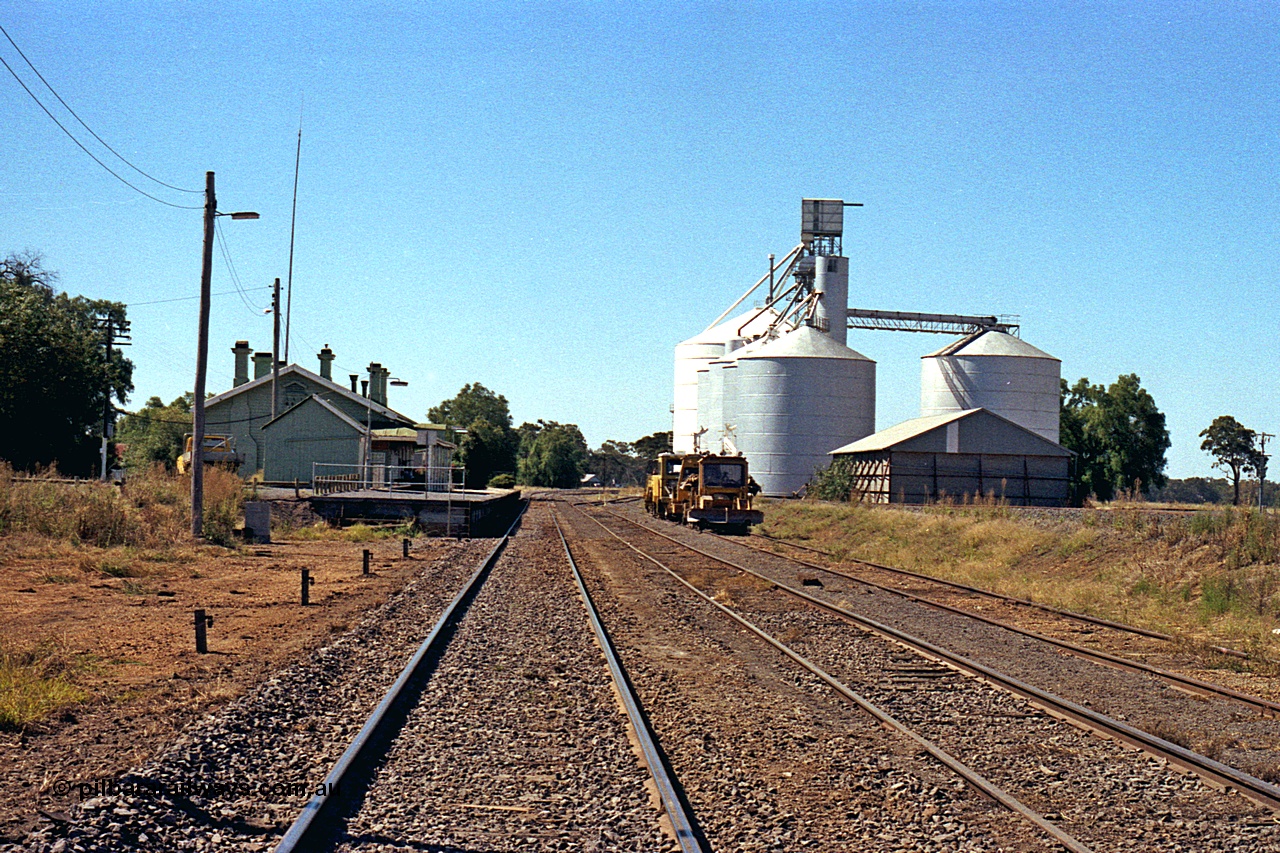 173-21
Murchison East, station yard overview looking north, goods shed and station building and platform, track machines, and horizontal grain bin with Murphy, with steel annex, and Ascom Jumbo style silo complexes.
