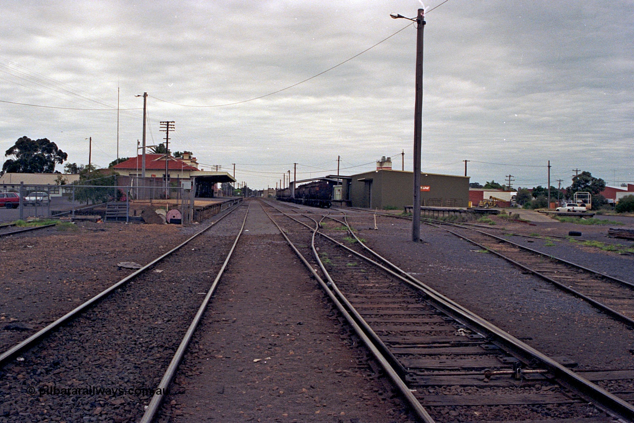 175-05
Shepparton station yard overview looking south, between No.1 and No.2 roads, points to No.3 and 4 roads, stabled fuel train in front of new style goods shed, loading platform, station building and platform on the left.
