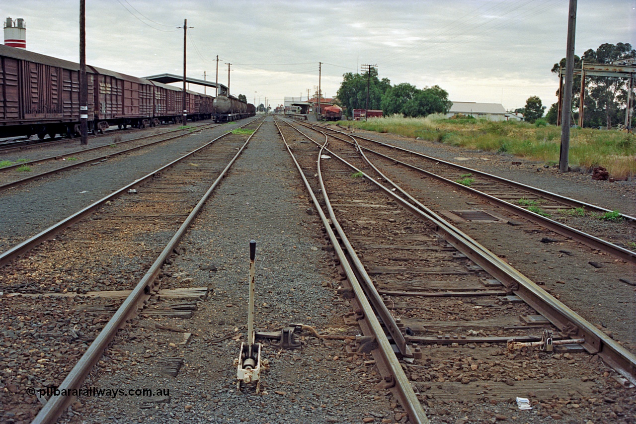 175-09
Shepparton station yard overview looking north, points and lever for No.2 to No.1 Rd cross-over which leads to the former Car Dock, now train examiner's siding, stabled goods and fuel trains on the left with the Freight Gate canopy, station building on the far right beyond examiner's siding.
