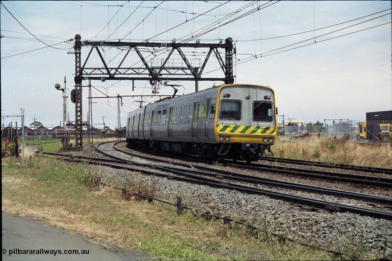 177-12
Newport, track view looking at Geelong - Werribee line, Newport Railway Workshops in the background, an up Werribee 3 car Comeng electric train is rounding the curve in 'The Met' livery.
