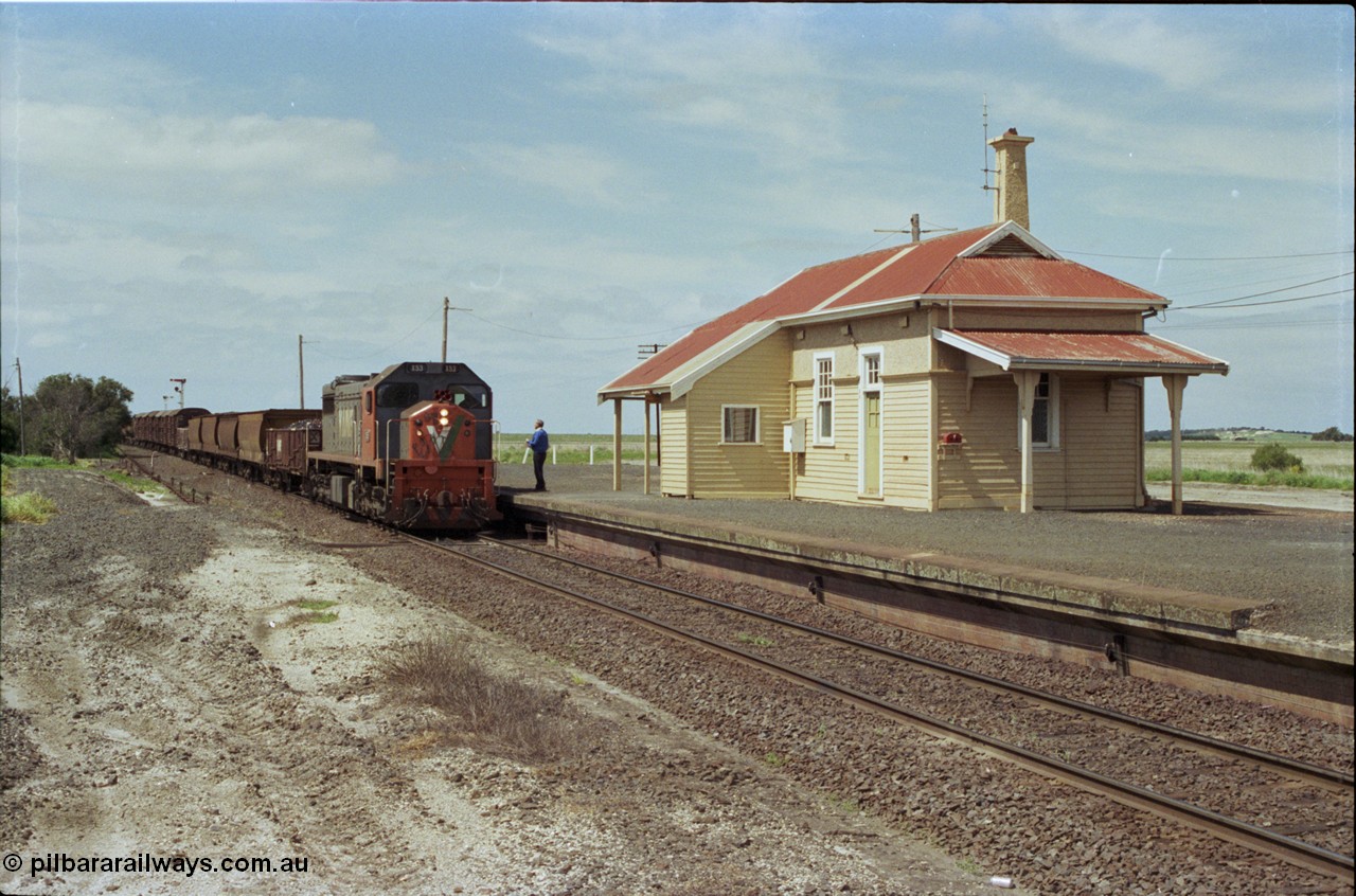 179-02
Gheringhap, station building and platform view with down broad gauge goods train 9153 behind V/Line X class loco X 53 with serial 75-800 a Clyde Engineering Rosewater SA built EMD model G26C, as the signaller readies to swap the electric staff from North Geelong C Box for a train order to Maroona.
Keywords: X-class;X53;Clyde-Engineering-Rosewater-SA;EMD;G26C;75-800;