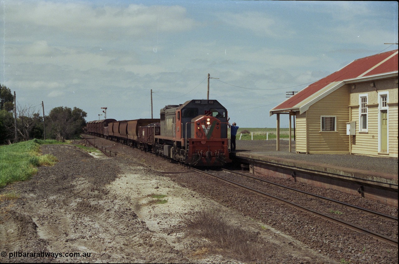 179-03
Gheringhap, station building and platform view with down broad gauge goods train 9153 behind V/Line X class loco X 53 with serial 75-800 a Clyde Engineering Rosewater SA built EMD model G26C, as the signaller swaps the electric staff from North Geelong C Box for a train order to Maroona.
Keywords: X-class;X53;Clyde-Engineering-Rosewater-SA;EMD;G26C;75-800;