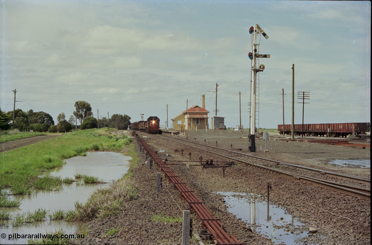 179-05
Gheringhap, yard overview looking east, broad gauge V/Line down goods train 9153 departs for Maroona with the signal on post 4 pulled off for the Maroona line, point rodding and interlocking is spaced away from the line as this location used to have double mainlines, on the right are gypsum waggons in Sidings B.
Keywords: X-class;X53;Clyde-Engineering-Rosewater-SA;EMD;G26C;75-800;