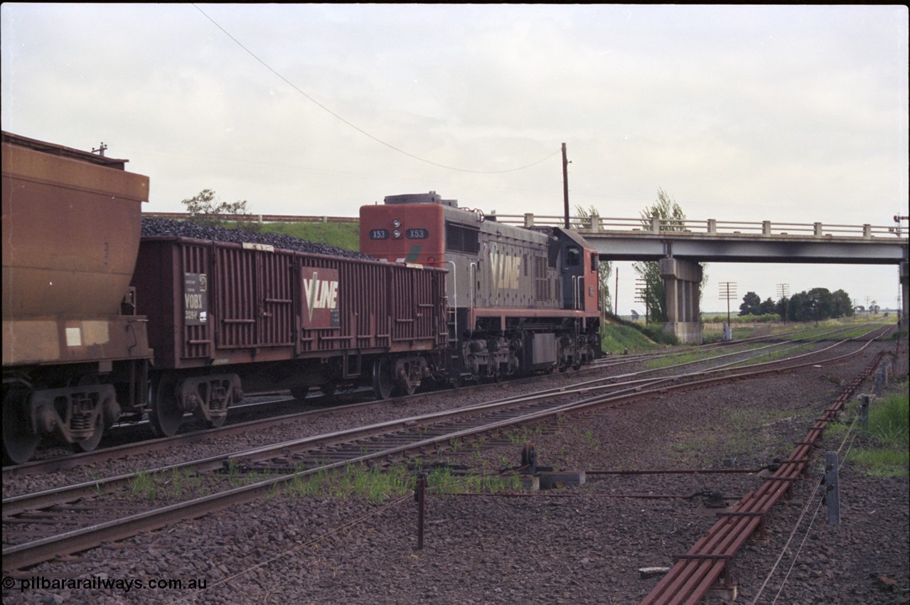 179-07
Gheringhap, track view looking west, broad gauge V/Line down goods train 9153 is bound for Maroona and beyond, the other lines are the Ballarat Line in the middle and Siding C on the right running under the Midland Highway overpass, point rodding and interlocking for Siding C points are visible, Siding C used to form part of the original up line back in double track days.
Keywords: X-class;X53;Clyde-Engineering-Rosewater-SA;EMD;G26C;75-800;