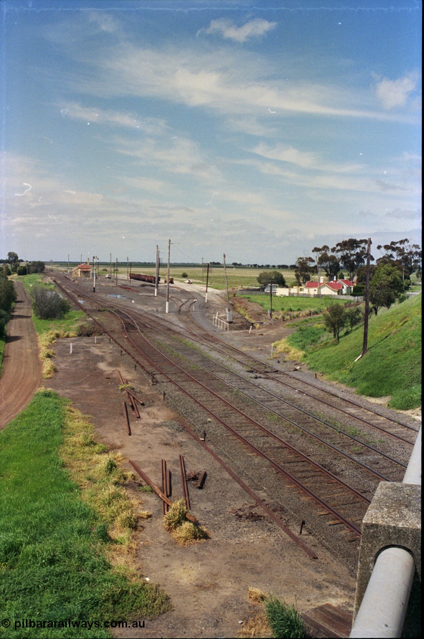 179-08
Gheringhap station yard overview from the elevated vantage point on the Midland Highway overpass, which was bought into use in 1967, looking east, the line on the left heading under the bridge is Siding C, in the middle is the Ballarat Line and then the Maroona Line, Sidings B with gypsum waggons can been seen to the right of the station building.
