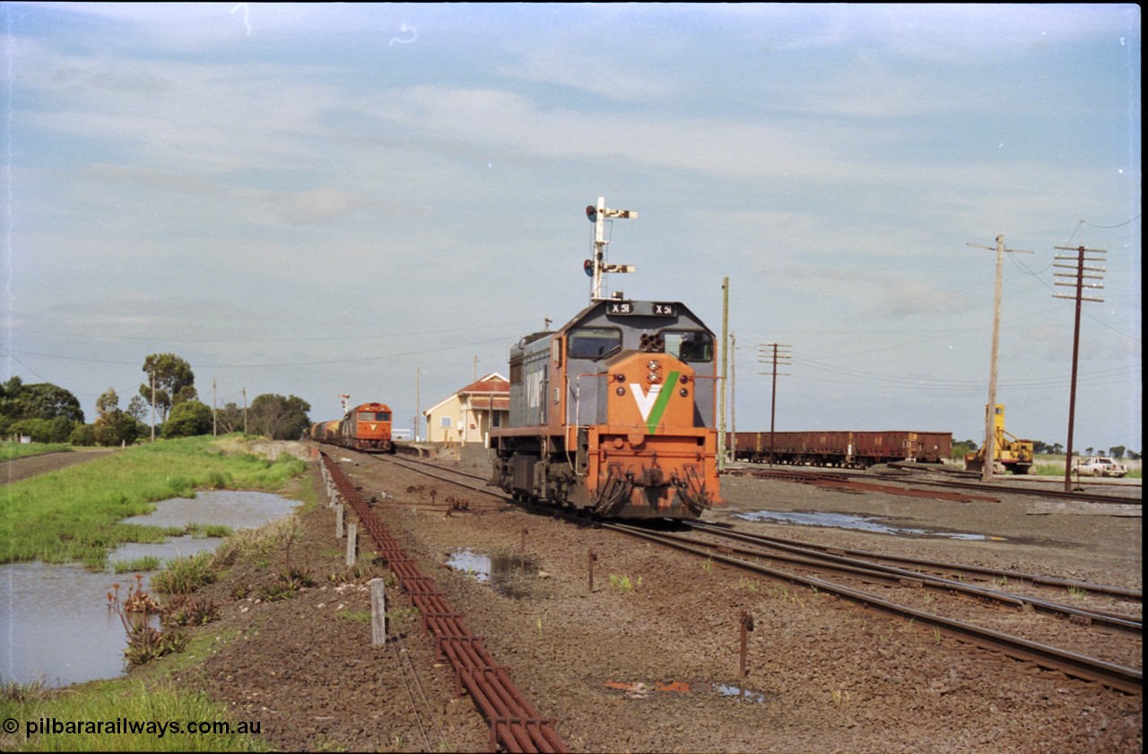 179-16
Gheringhap, V/Line broad gauge X class locomotive X 51 Clyde Engineering EMD model G26C serial 75-798 has been removed from train 9169 and is running light engine to stable in Siding C, the disc for Siding C on signal post 4 can just be made out above the loco's cab, 9169 holds the mainline at the station and a rake of gypsum waggons sits in Sidings B on the right.
Keywords: X-class;X51;Clyde-Engineering-Rosewater-SA;EMD;G26C;75-798;