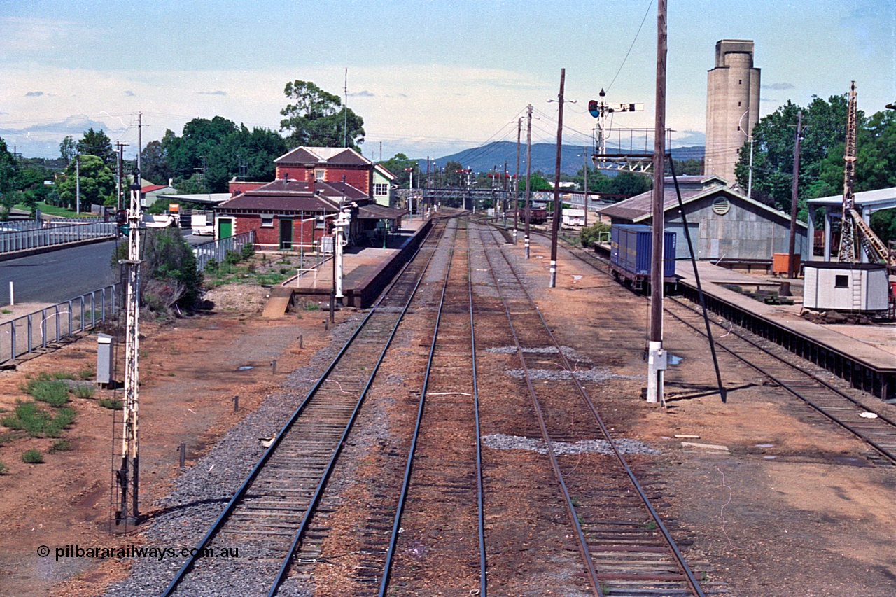 180-12
Wangaratta, rationalised station yard overview looking south from footbridge, removed crossovers from No.2 and 3 to 4 Roads can still be seen in the dirt, also removed Siding A at left of station platform, station building, semaphore signal posts, goods shed and loading platform with slewing derrick crane.
