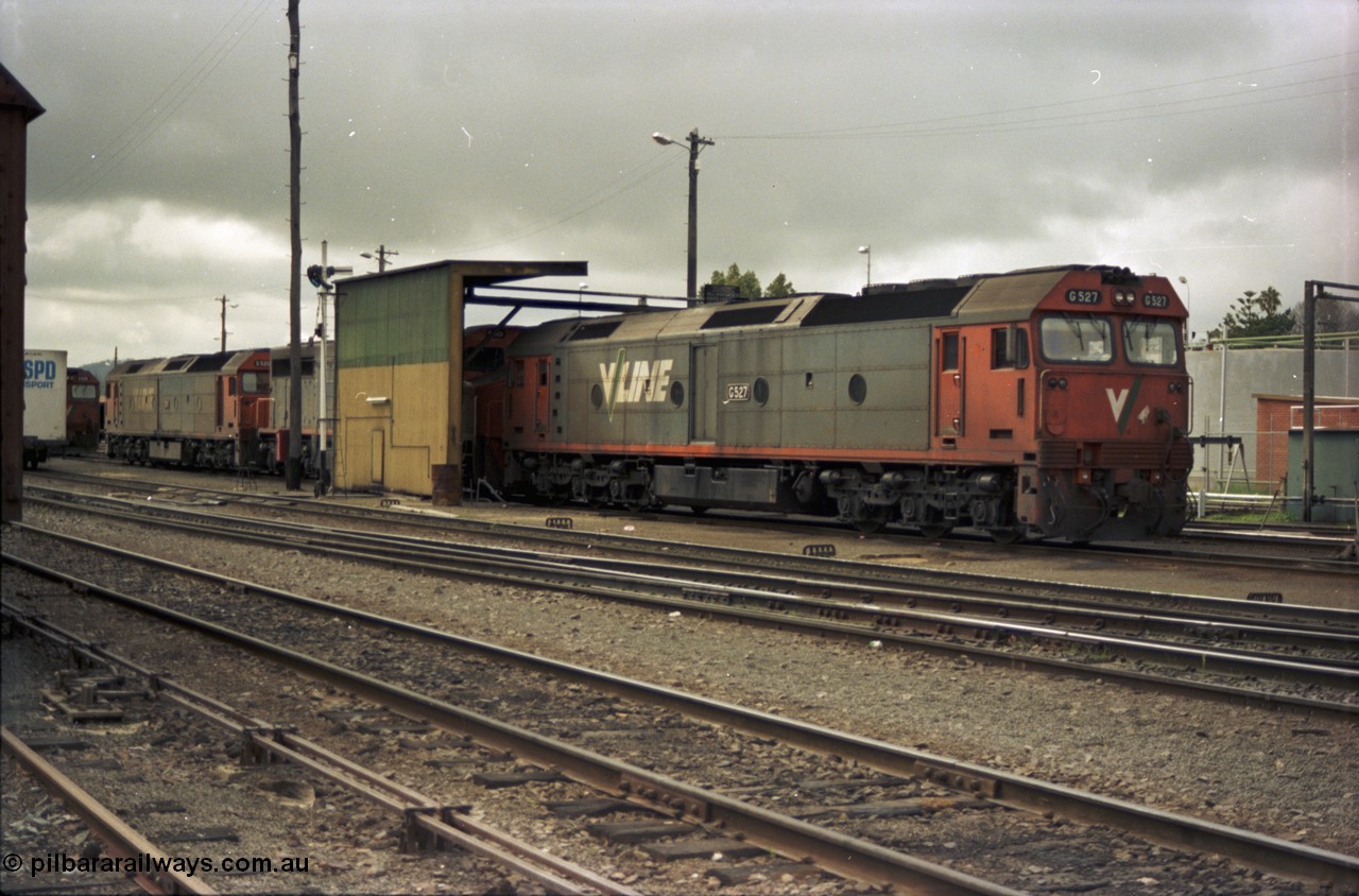 184-01
Albury loco depot fuel point, V/Line standard gauge locos lined up awaiting the Sunday run of goods trains back to Melbourne, G class G 527 Clyde Engineering EMD model JT26C-2SS serial 88-1257, C class C 503 Clyde Engineering EMD model GT26C serial 76-826 and G classes G 520 serial 85-1233 and partly obscured G 525 serial 86-1238, semaphore signal and rear of fuel point, view across yard, point rodding.
Keywords: G-class;G527;Clyde-Engineering-Somerton-Victoria;EMD;JT26C-2SS;88-1257;C-class;C503;GT26C;76-826;G520;85-1233;G525;86-1238;