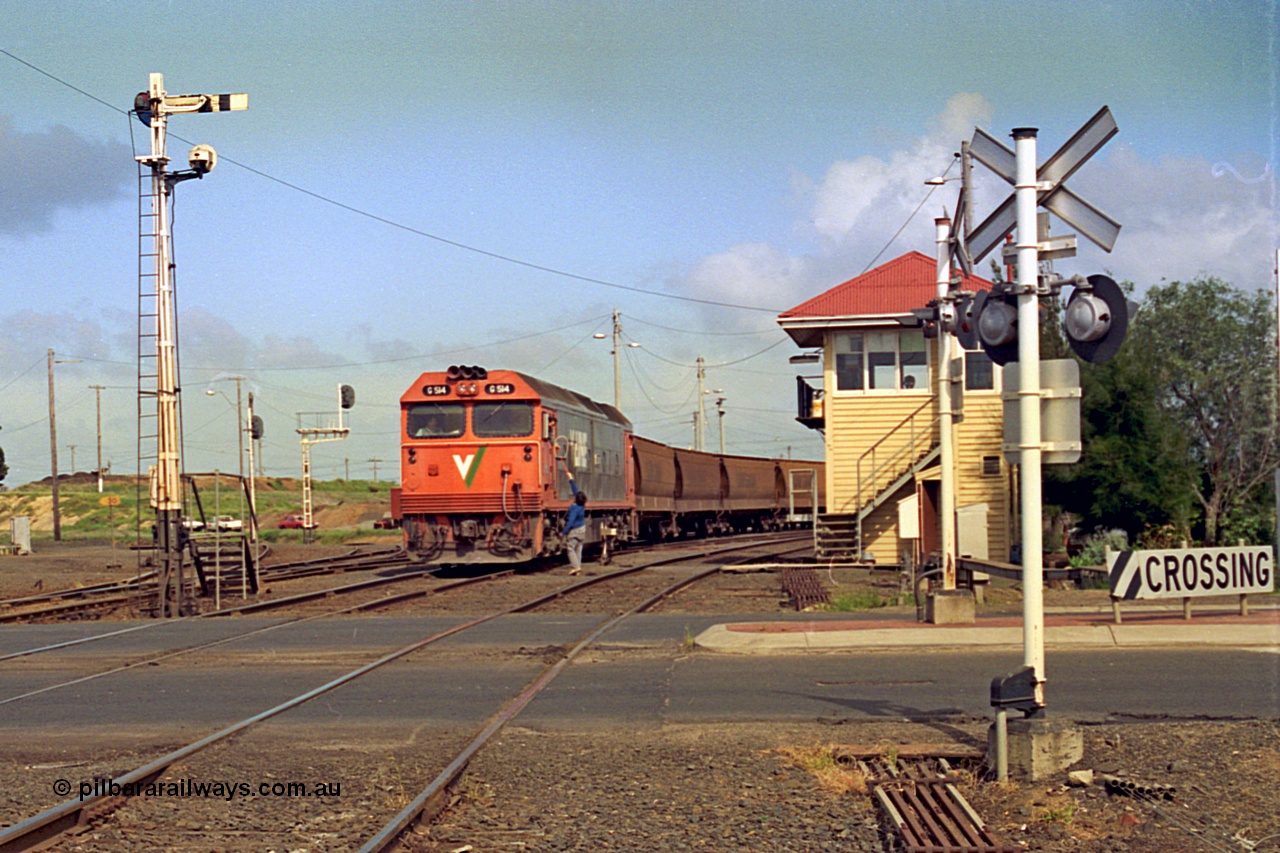 185-06
North Geelong C Box looking across the Separation Street grade crossing as a V/Line G class locomotive G 514 Clyde Engineering EMD model JT26C-2SS serial 85-1242 departs North Geelong Yard with 9121 empty grain train, the driver has just collected the Gheringhap electric staff off the signaller, the tracks to the grain loop and the Loop Line to Melbourne are curving around to the left beyond the mechanical and electric signal posts.
Keywords: G-class;G514;Clyde-Engineering-Rosewater-SA;EMD;JT26C-2SS;85-1242;