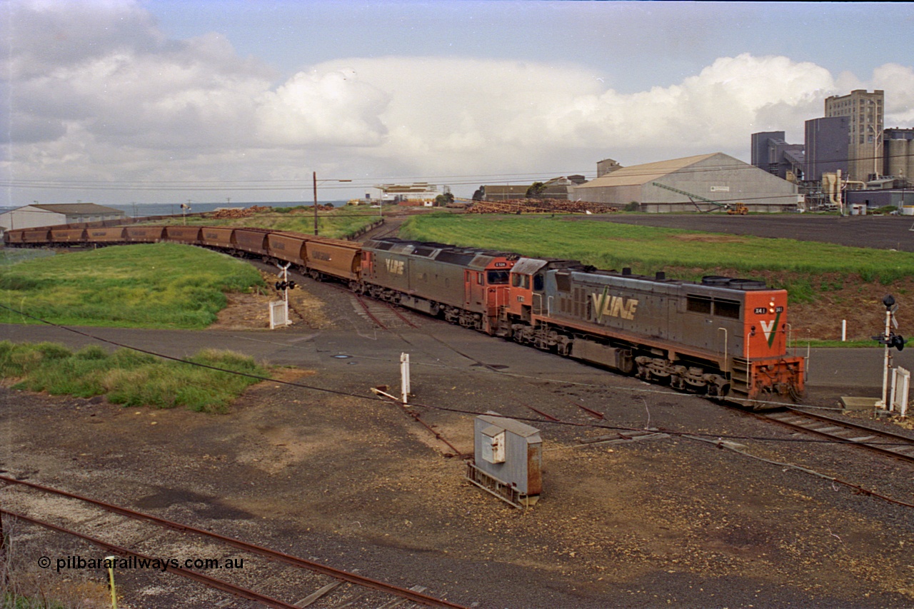 185-12
North Geelong Grain Loop view from Corio Quay Road across Access Road grade crossing with the tracks to Corio Quay at the very bottom of image, as the grain train behind V/Line locos X class locomotive X 41 Clyde Engineering EMD model G26C serial 70-704 long end leading and G class locomotive G 528 Clyde Engineering EMD model JT26C-2SS serial 88-1258 having past the Home Signal and crossing the former tracks for the Freezing Works Sidings.
Keywords: X-class;X41;Clyde-Engineering-Granville-NSW;EMD;G26C;70-704;
