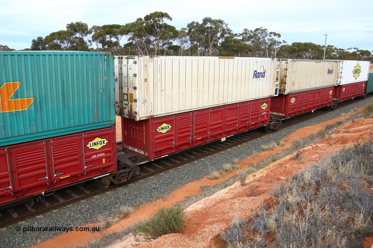 160524 3796
West Kalgoorlie, 2PM6 intermodal train, RRGY 7125 platform 2 of 5-pack articulated skeletal waggon set, one of fifty originally built by AN Rail Islington Workshops in 1996-97 as type RRBY, later rebuilt with 48' intermediate decks and recoded to RRGY, with a Linfox 40' half height side door LSDU 6940090 double stacked with a RAND Refrigerated Logistics 46' 6