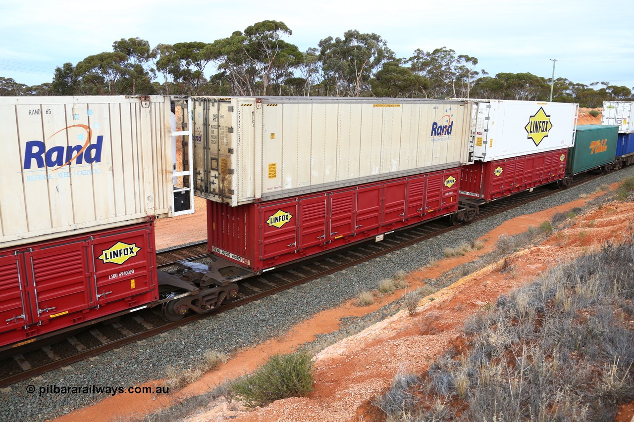 160524 3797
West Kalgoorlie, 2PM6 intermodal train, RRGY 7125 platform 3 of 5-pack articulated skeletal waggon set, one of fifty originally built by AN Rail Islington Workshops in 1996-97 as type RRBY, later rebuilt with 48' intermediate decks and recoded to RRGY, with a Linfox 40' half height side door LSDU 6940054 double stacked with a RAND Refrigerated Logistics 46' 6