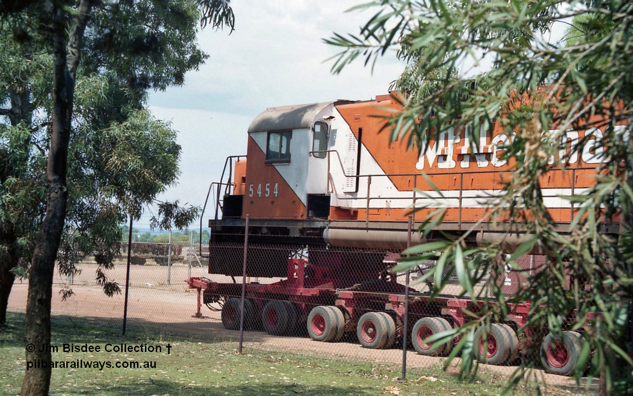 20861
Bassendean, Goninan workshops, sitting outside the locked gates having just been bought down from Port Hedland, Mt Newman Mining's AE Goodwin ALCo C636 unit 5454 serial G6012-3 on a ninety six wheel road float. 5454 will be rebuilt into CM40-8M unit 5641 by June 1992. Image taken January 1992.
Jim Bisdee photo.
Keywords: 5454;AE-Goodwin;ALCo;C636;G6012-3;