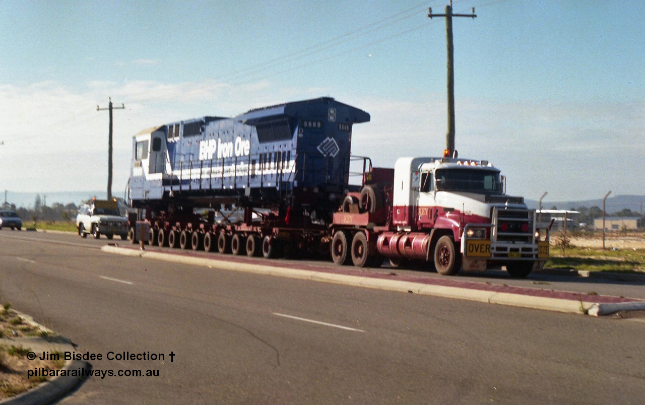 24134
Bassendean, Collier Road, Key Transport hauling the final BHP Iron Ore Goninan GE rebuilt CM40-8M unit 5669 serial 8412-02 / 95-160, which is actually an CM40-8MEFI as the final three had electronic fuel injection fitted to their 7FDL-16 engines. 5669 was rebuilt from Comeng NSW built ALCo M636 model 5486 serial C6084-2. July 1995.
Jim Bisdee photo.
Keywords: 5669;Goninan;GE;CM40-8EFI;8412-02/95-160;rebuild;Comeng-NSW;ALCo;M636C;5486;C6084-2;