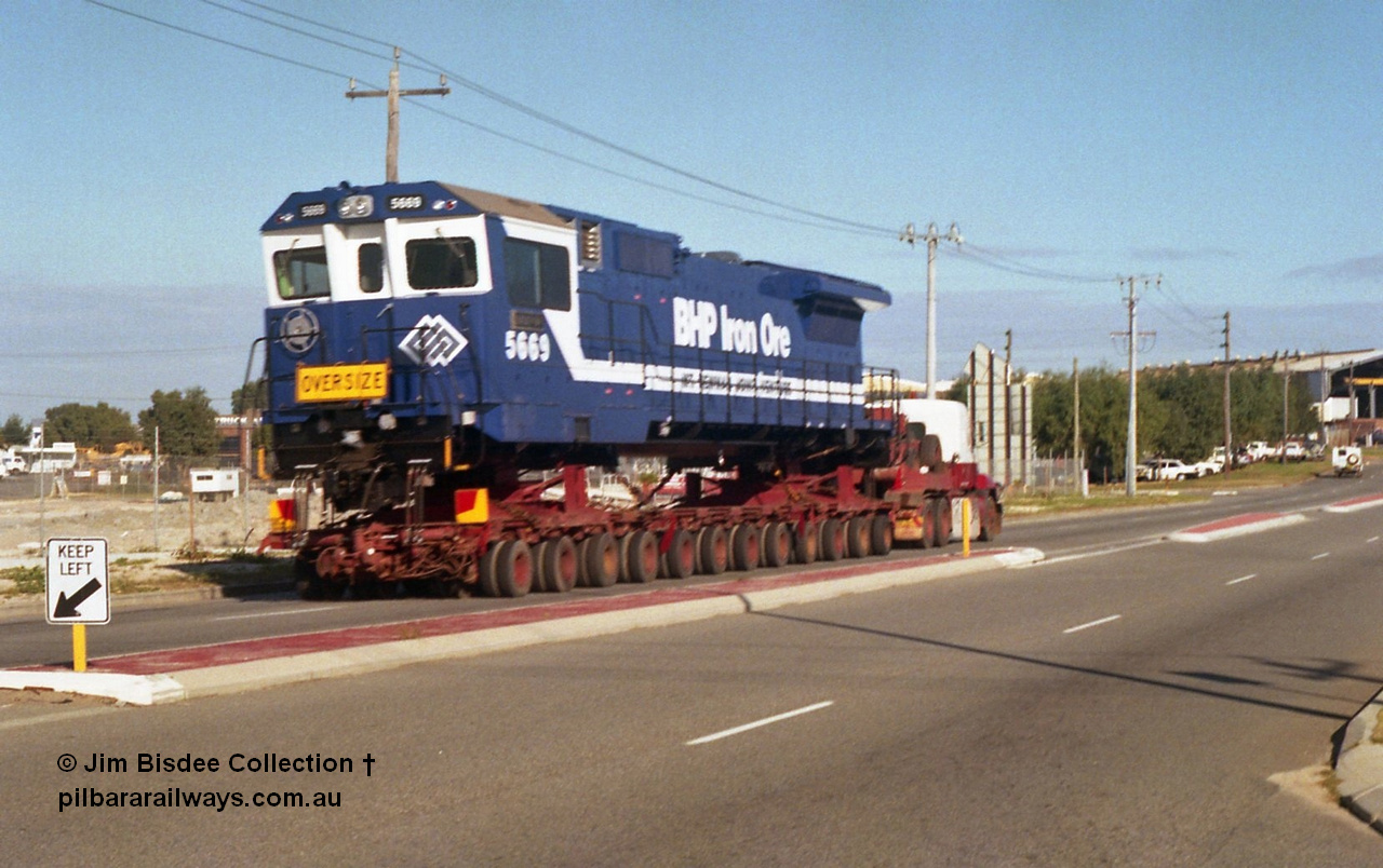 24135
Bassendean, Collier Road, Key Transport hauling the final BHP Iron Ore Goninan GE rebuilt CM40-8M unit 5669 serial 8412-02 / 95-160, which is actually an CM40-8MEFI as the final three had electronic fuel injection fitted to their 7FDL-16 engines. 5669 was rebuilt from Comeng NSW built ALCo M636 model 5486 serial C6084-2. July 1995.
Jim Bisdee photo.
Keywords: 5669;Goninan;GE;CM40-8EFI;8412-02/95-160;rebuild;Comeng-NSW;ALCo;M636C;5486;C6084-2;
