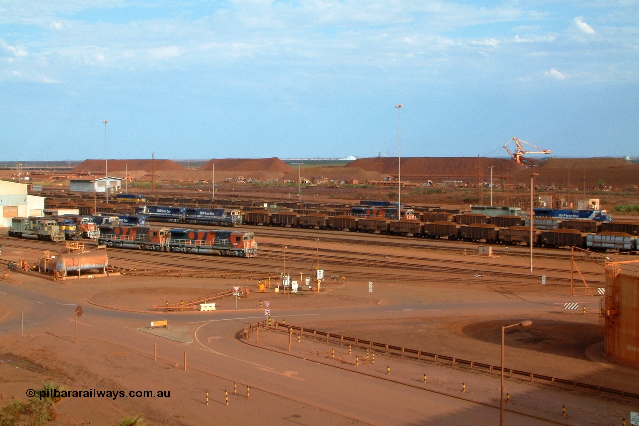 041119 163032r
Nelson Point, how is this for a Parade of Pilbara Power? On the afternoon of Friday the 19th of November 2004 a photo was managed with no less than fourteen locos in the shot, seven at the workshops, and seven on trains at the car dumper roads. Locos in the frame are: 3085, 3080, 3092, 5639, 5636, 5667, 6074 at the workshops and, 6073, 3082, 3079, 5640, 5669, 3078, and 5630 on the car dumper roads. Models are EMD SD40R and SD40-2, GE AC6000 and Goninan GE CM40-8M.
